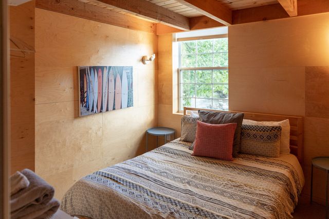 Chambre chaleureuse avec lit queen, poutres apparentes et tableau coloré